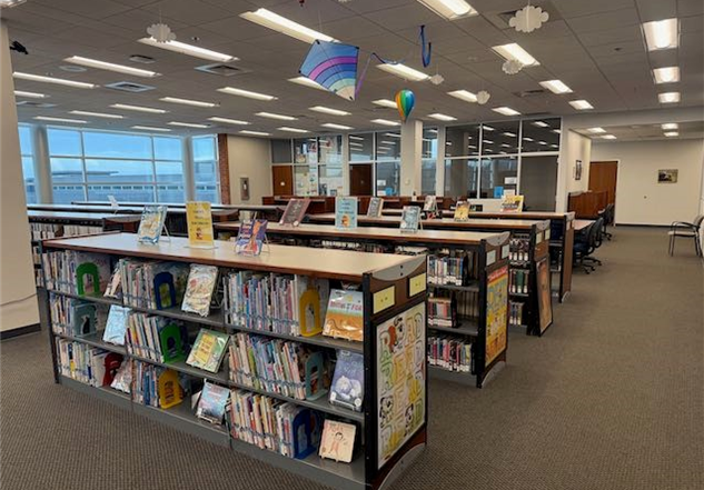 Children's collection with books on bookshelves with posters and kites and hot air bolloons hanging from the ceiling